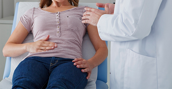 a woman holding her stomach in pain with a doctor diagnosing her 