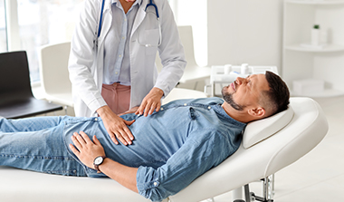 a man in pain as a gastroenterologist examines his stomach